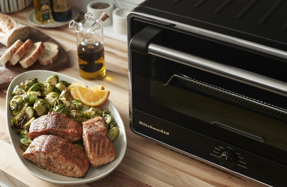 Kitchen counter with a plate of brussels sprouts and salmon next to KitchenAid® countertop oven
