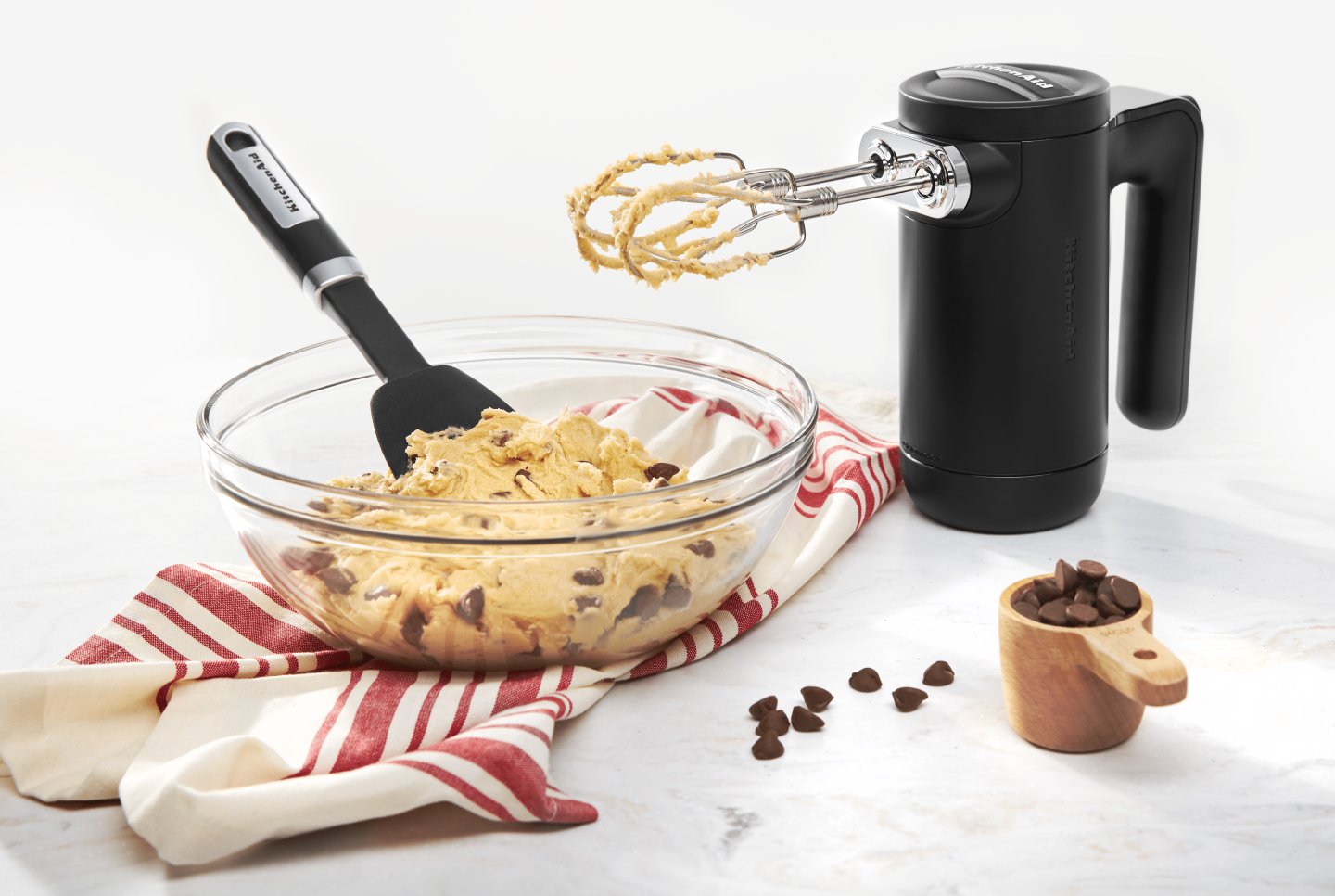 Black KitchenAid® hand mixer with bowl of chocolate chip cookie dough