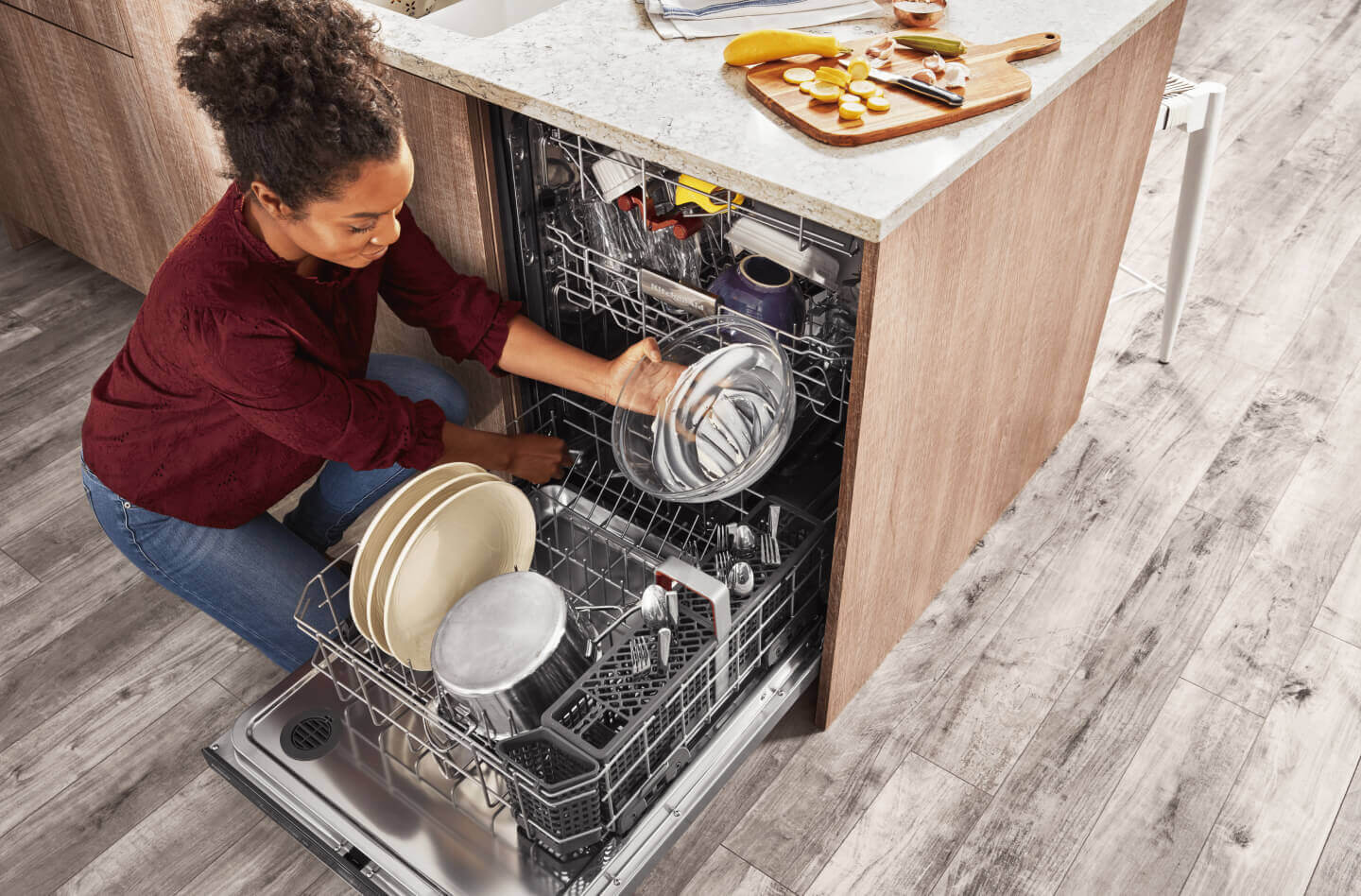 Person loading glass bowl into the bottom rack of a dishwasher