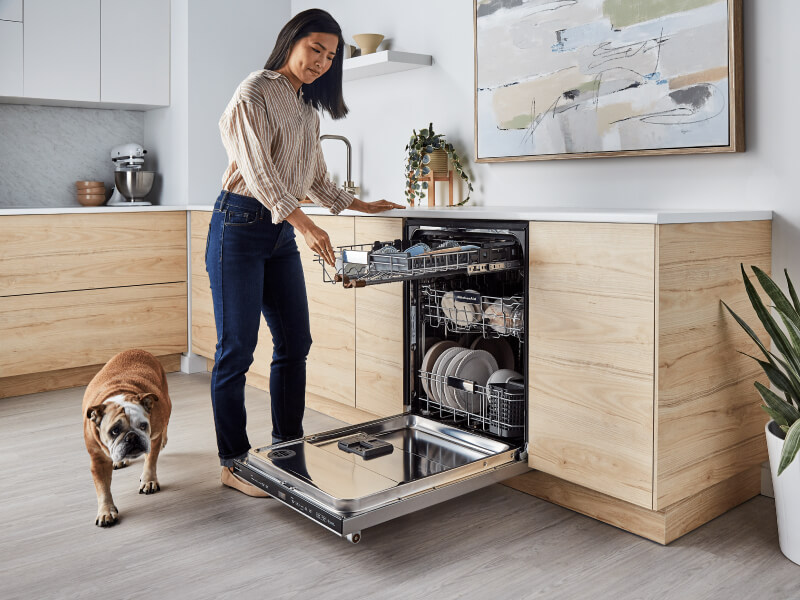 Person loading the third rack of a panel-ready dishwasher 
