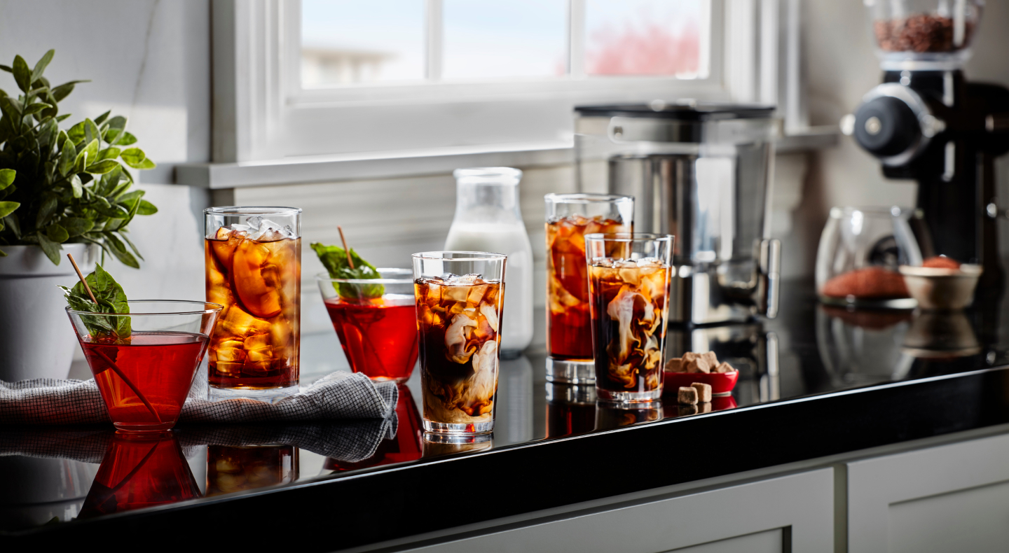 Glasses of iced black tea with peach slices and iced herbal tea with mint garnishes