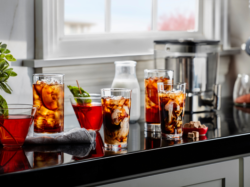 Glasses of iced black tea with peach slices and iced herbal tea with mint garnishes
