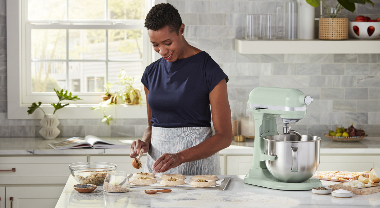 A woman placing filling on pastries for baking