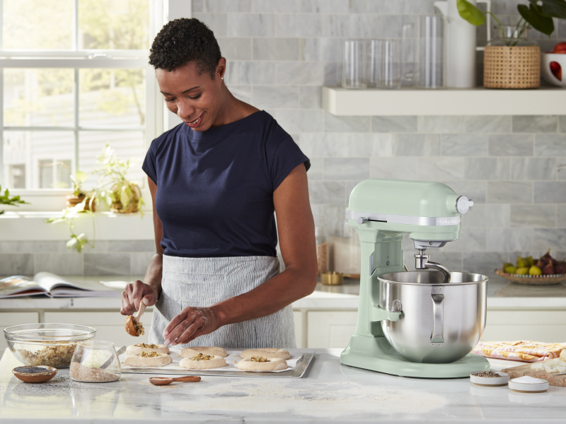 A woman placing filling on pastries for baking