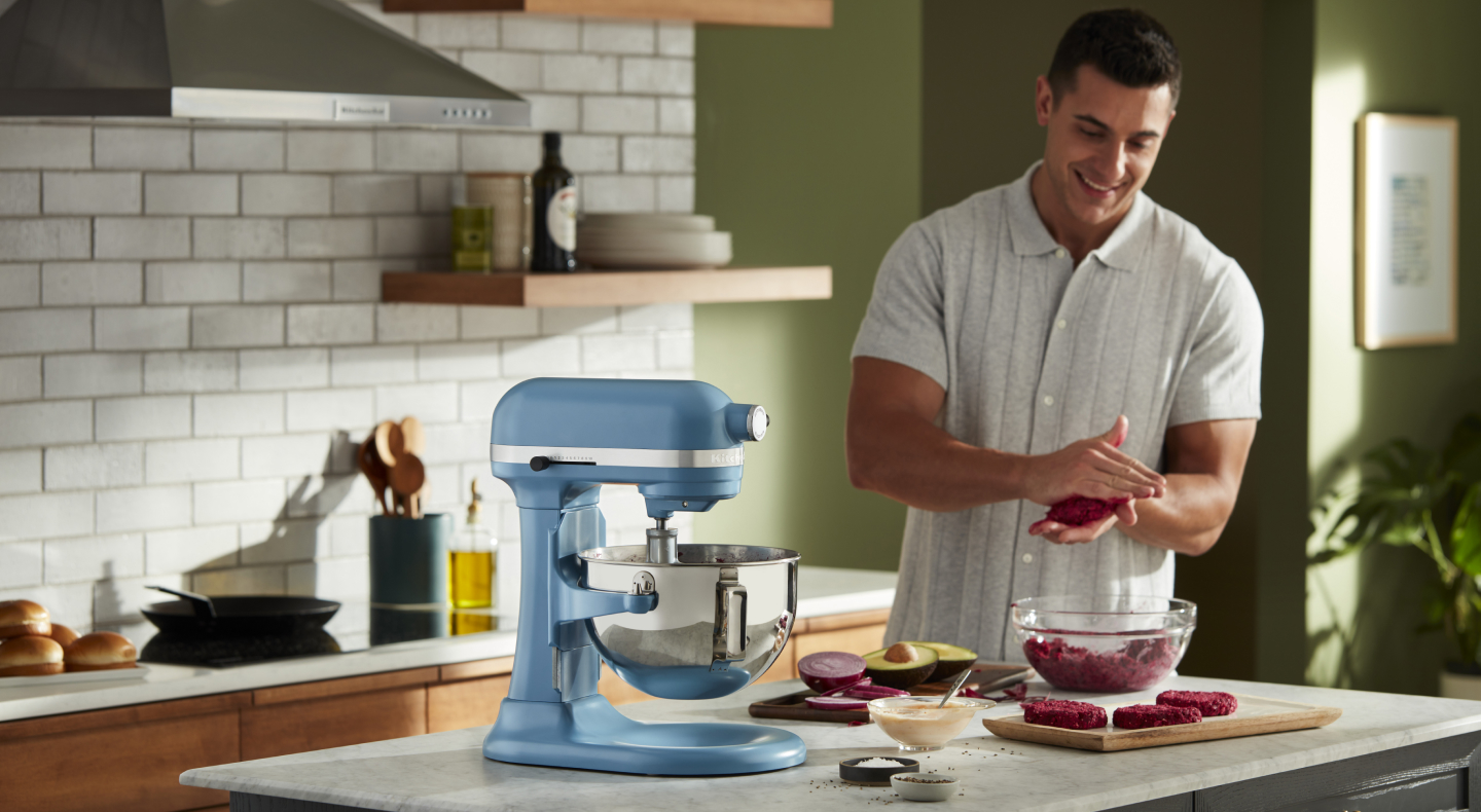 A man flattening patties next to a blue bowl-lift KitchenAid® stand mixer