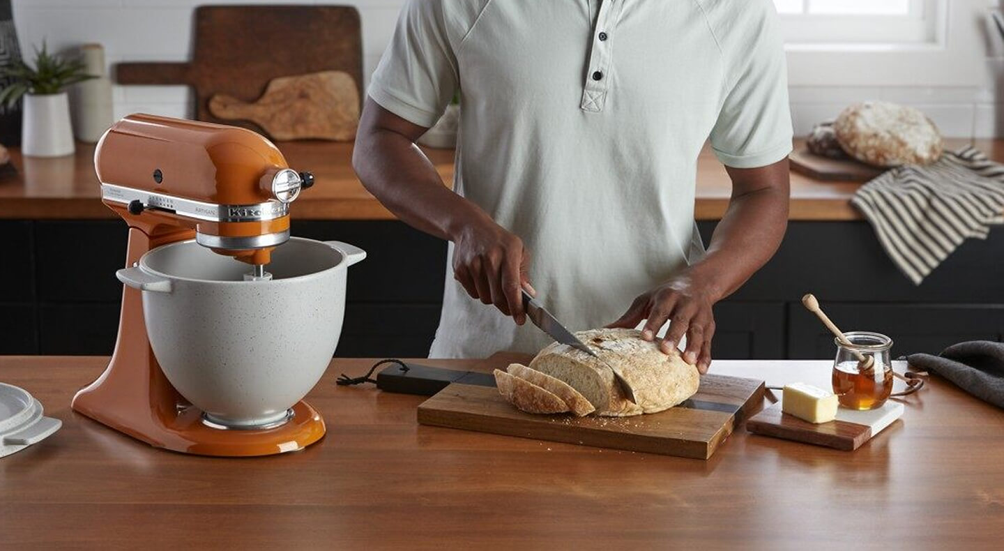 A person slicing into a round loaf of bread