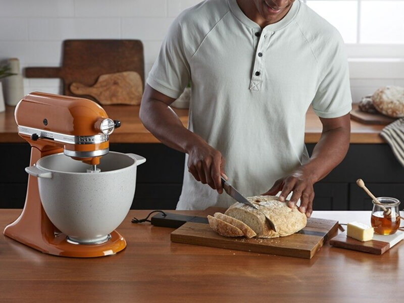 A person slicing into a round loaf of bread