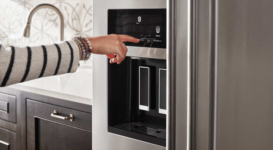 Finger touching the control pad of a refrigerator water dispenser