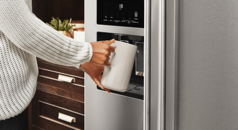 Woman filling a container with water from a refrigerator