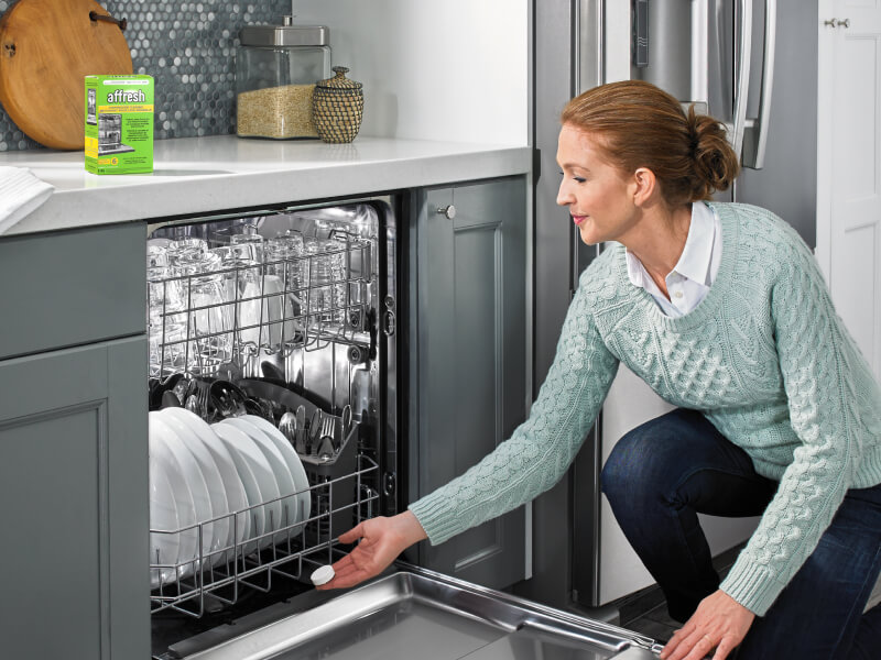 A person using an affresh® dishwasher cleaner tablet to clean their dishwasher