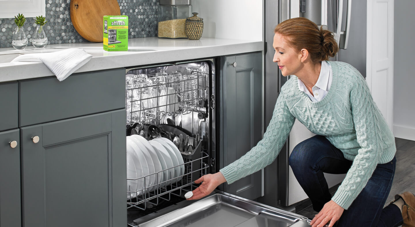A person using an affresh® dishwasher cleaner tablet to clean their dishwasher