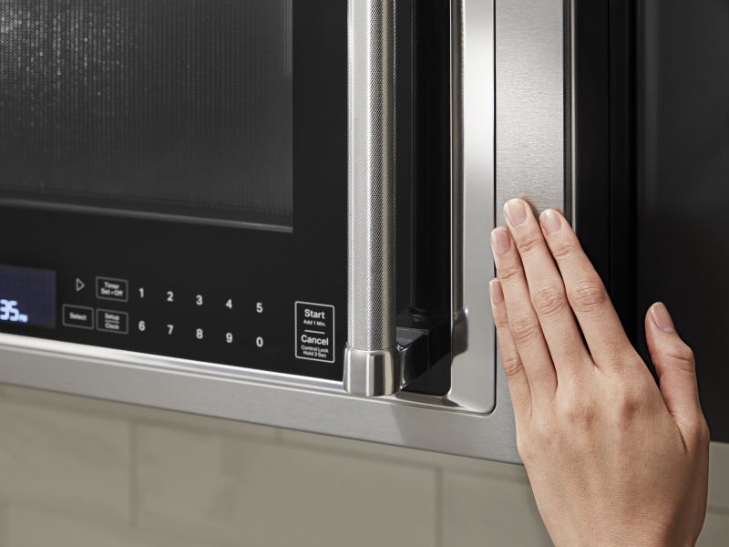 Hand closing a KitchenAid® over the range microwave