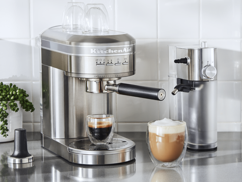 Espresso in a silver KitchenAid® Espresso Machine next to Automatic Milk Frother Attachment