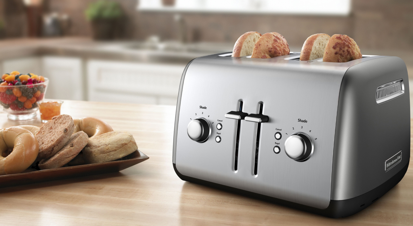 Bagel slices in a silver 4-slice KitchenAid® toaster on a modern kitchen counter.