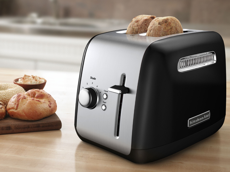 Bagel slices in a silver KitchenAid® toaster on a modern kitchen counter.