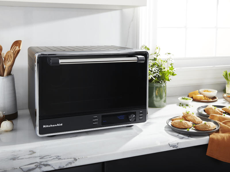 A black KitchenAid® air fryer and fresh empanadas on a countertop