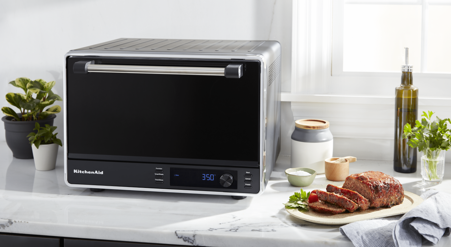 Cooked meat next to a black KitchenAid® countertop oven