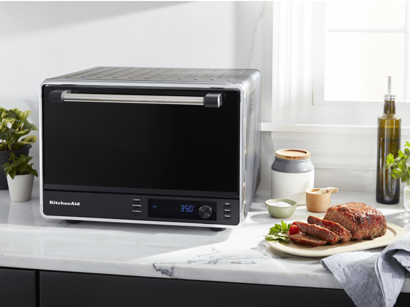 Cooked meat next to a black KitchenAid® countertop oven