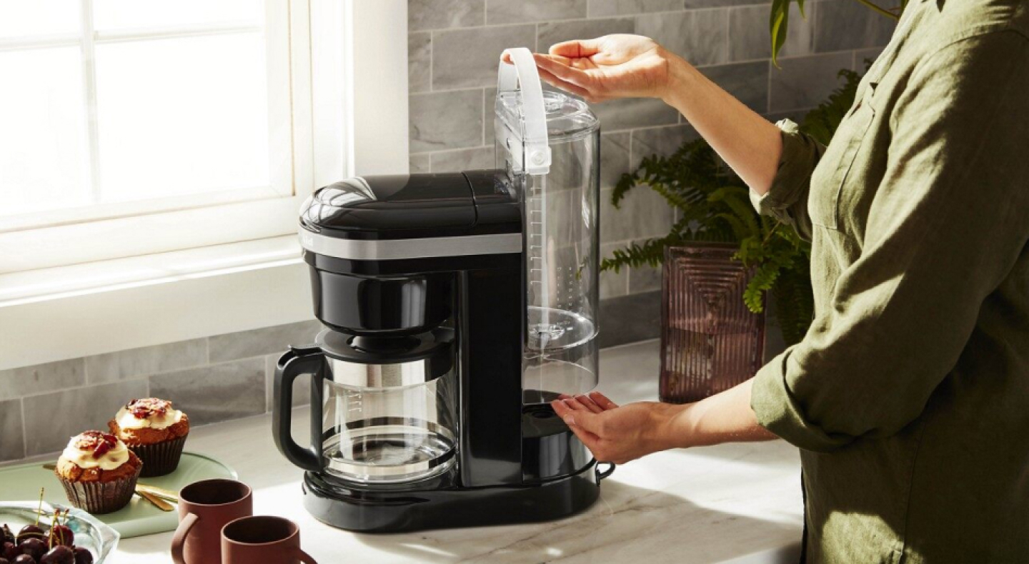 Woman replacing water tank in coffee machine