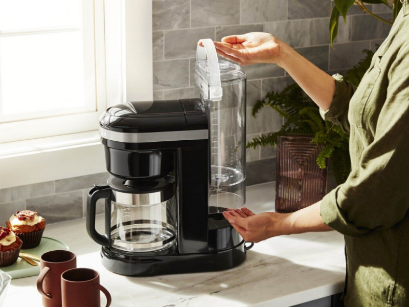 Woman replacing water tank in coffee machine