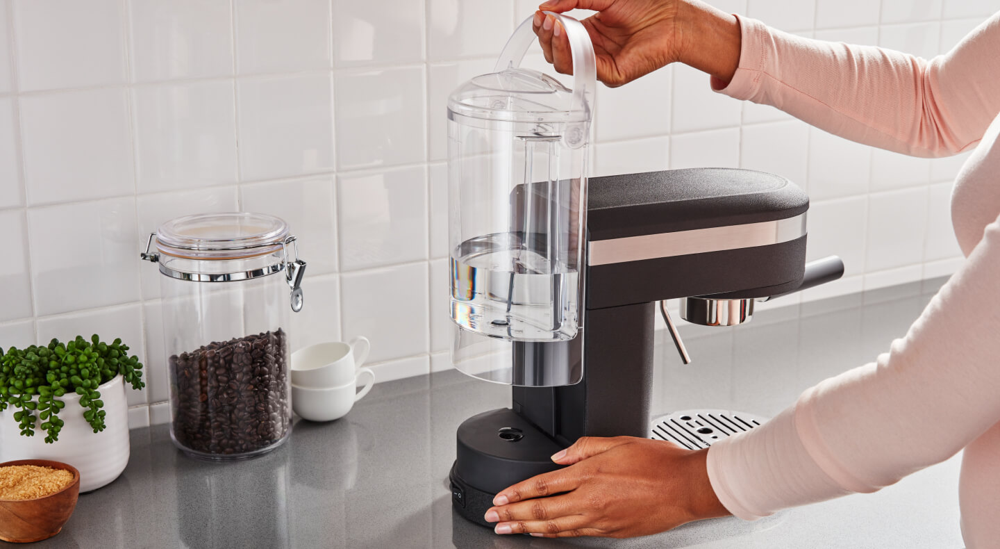 Hand removing the water tank of a KitchenAid® espresso machine