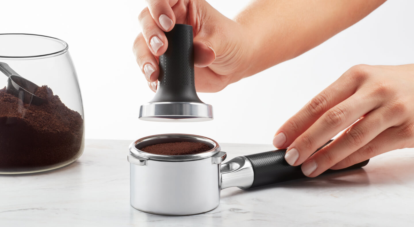 Hand tamping coffee grounds into portafilter