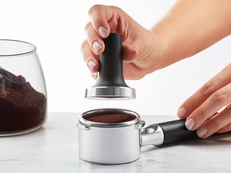 Hand tamping coffee grounds into portafilter