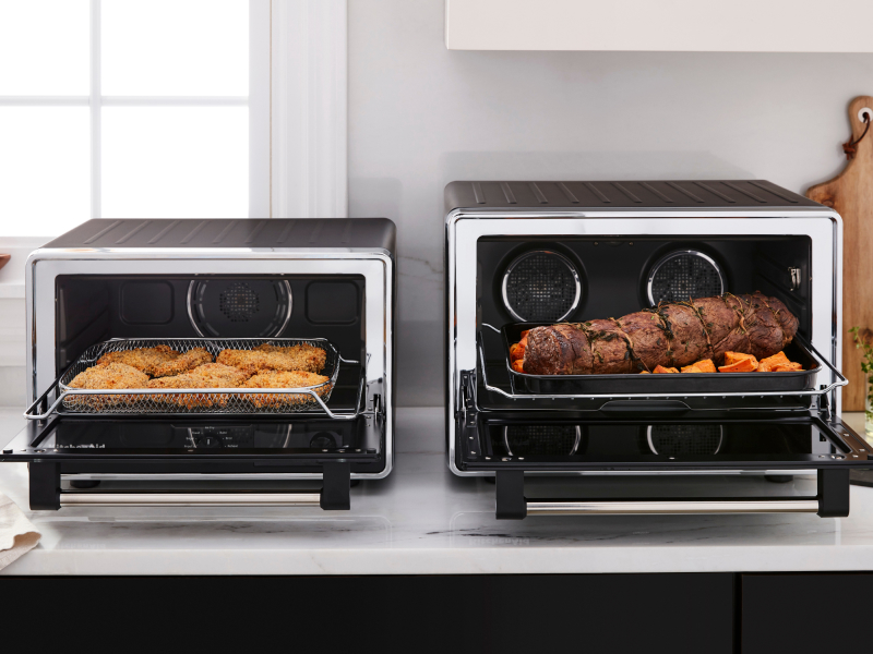Two KitchenAid® countertop ovens with freshly prepared food on a modern kitchen counter.