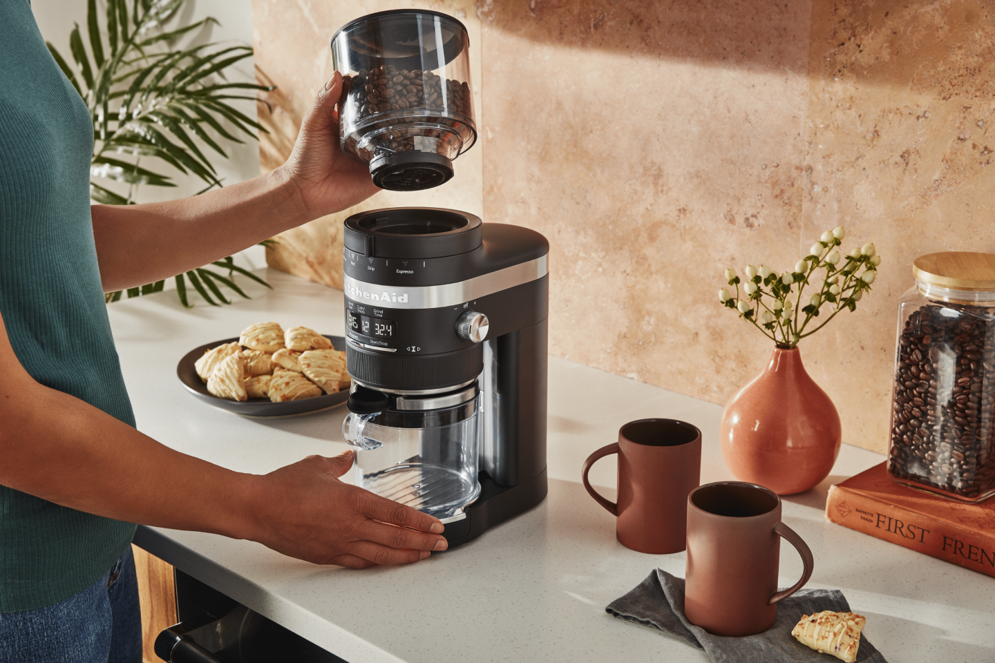 Woman placing top of coffee grinder on base of grinder