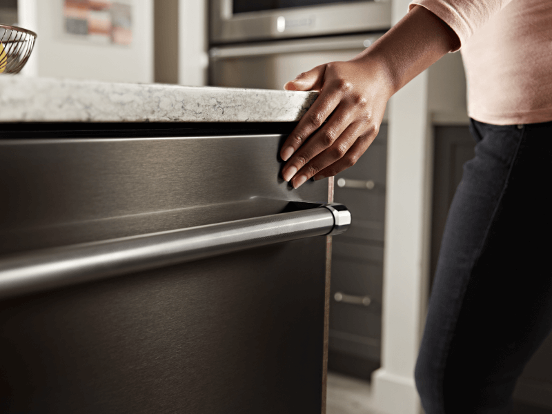Person closing a KitchenAid® top control dishwasher