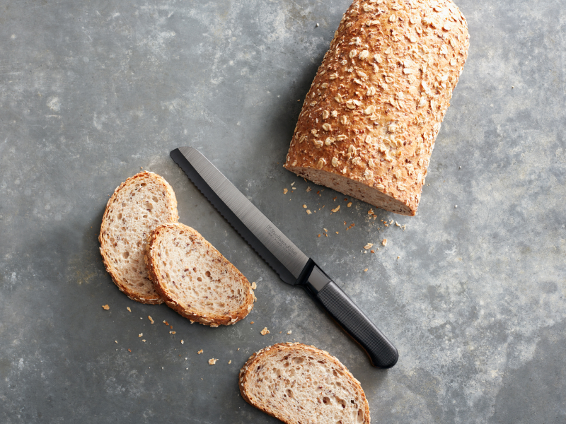 Half sliced loaf of bread on countertop with knife