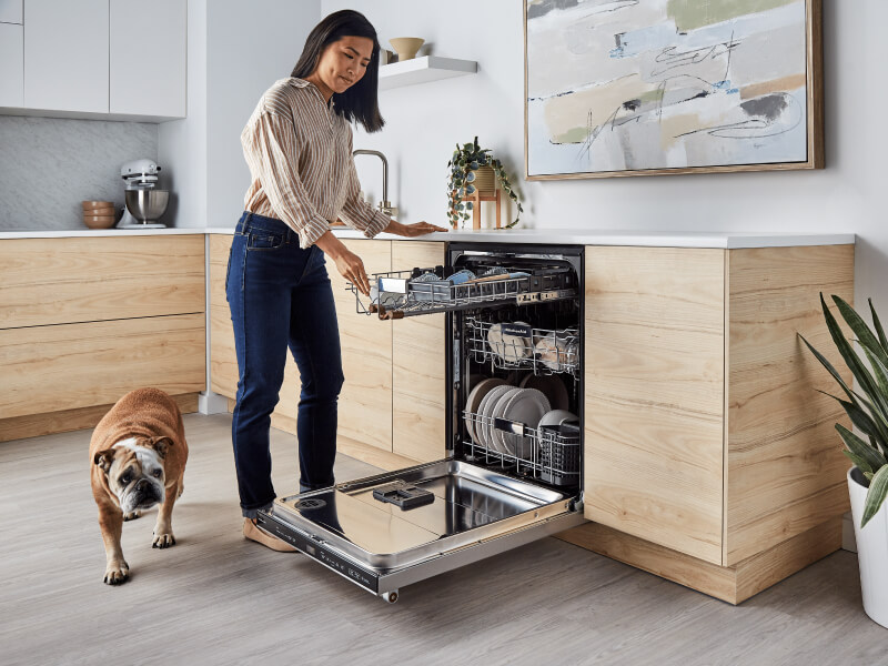Person picking up dirty bowl to load into dishwasher