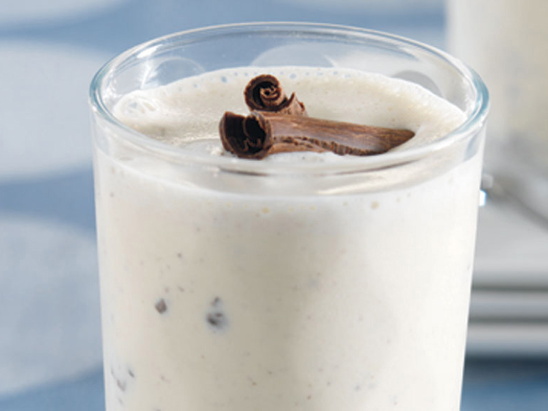 Close-up of vanilla milkshake with mix-ins and cinnamon sticks on top