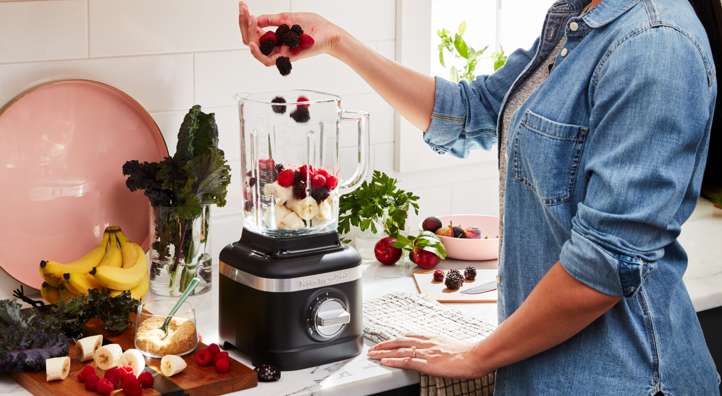 Person adding fruit to a blender