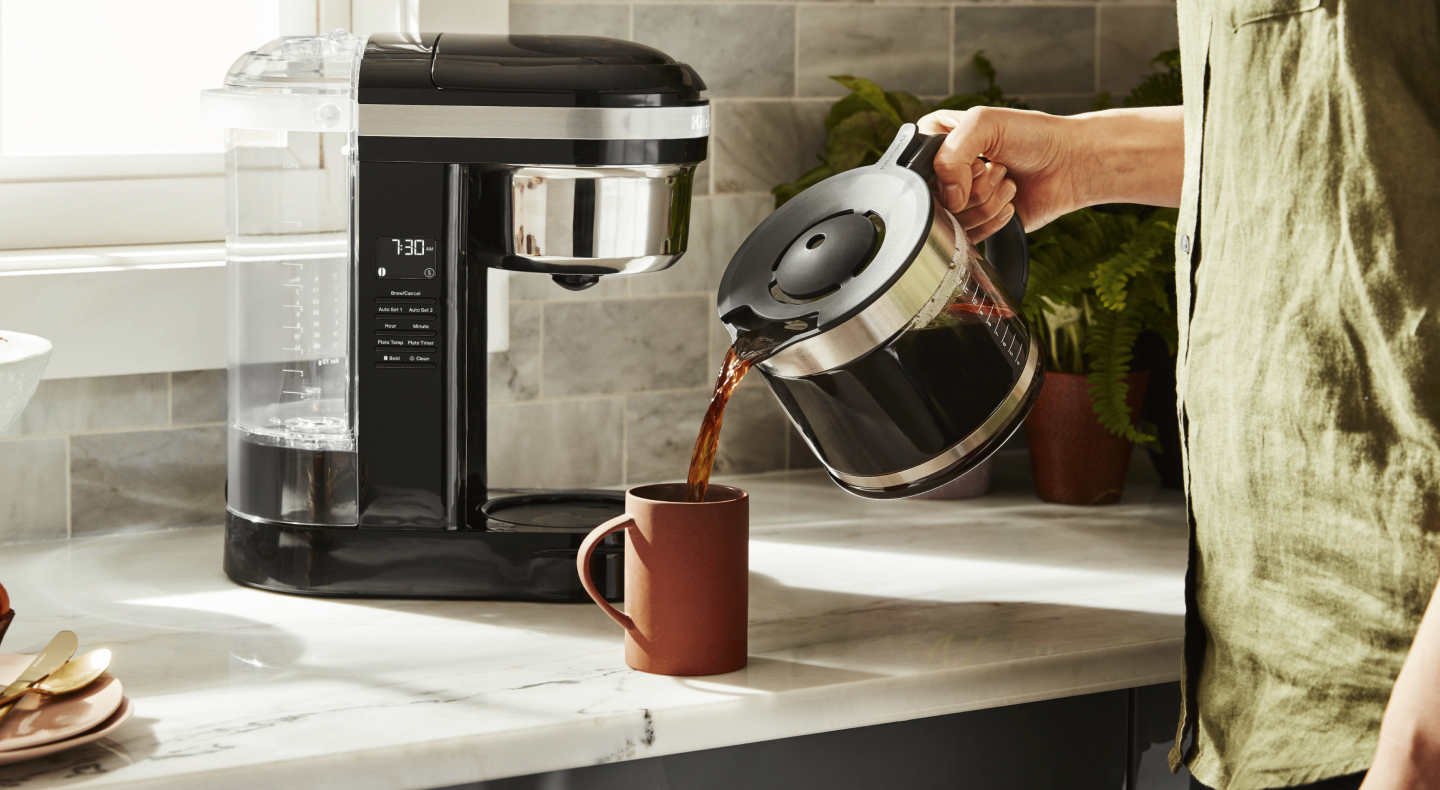 Person pouring coffee from a pot into a mug