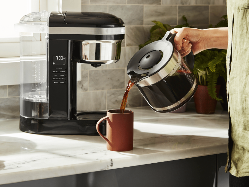 Person pouring coffee from a pot into a mug