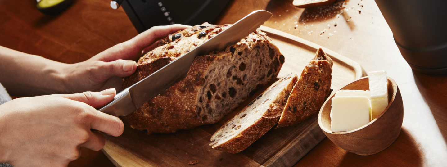 Person slicing freshly baked bread on a cutting board