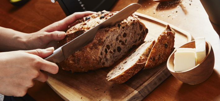 Person slicing freshly baked bread on a cutting board