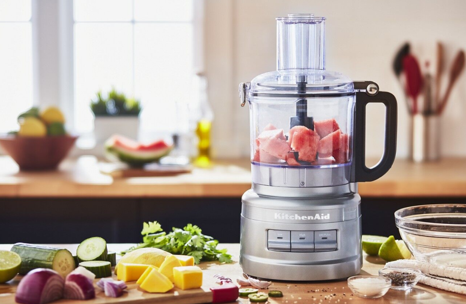 Watermelon in a food processor on counter surrounded by ingredients