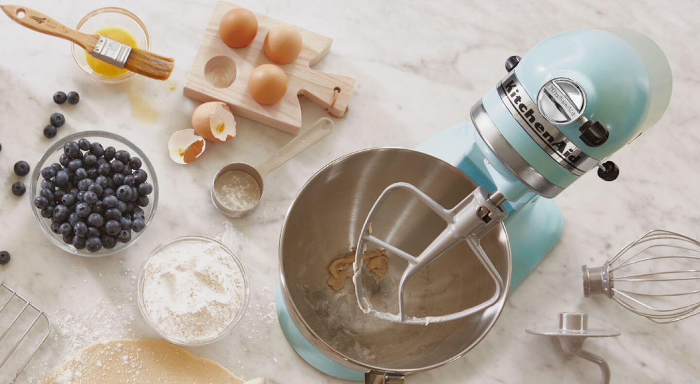 Birds-eye view of light blue stand mixer surrounded by blueberry muffin ingredients