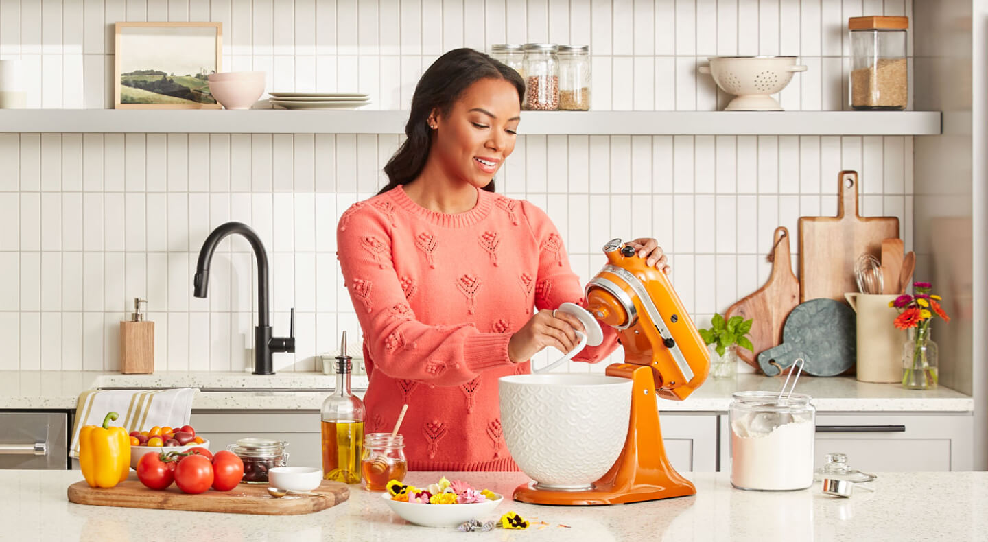 Person attaching the KitchenAid® Dough Hook accessory to an orange stand mixer