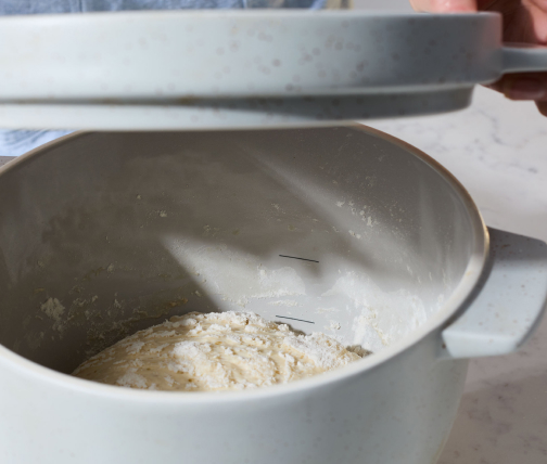 Person adding Bread Bowl lid to proof dough