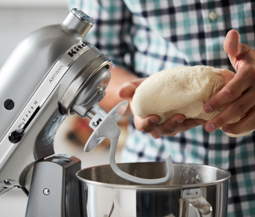 Person shaping dough taken from a stand mixer bowl