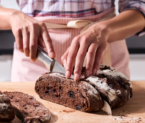 Person slicing a load of baked bread