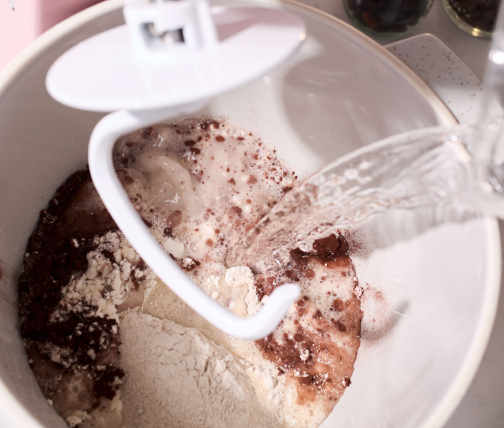 Person adding bread ingredients to stand mixer bowl