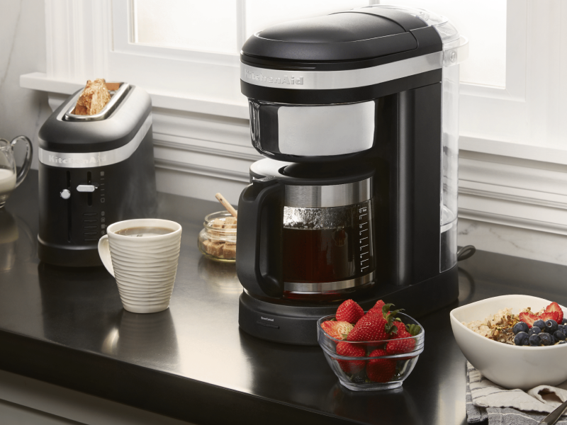 KitchenAid® coffee maker on countertop with coffee drink and breakfast foods