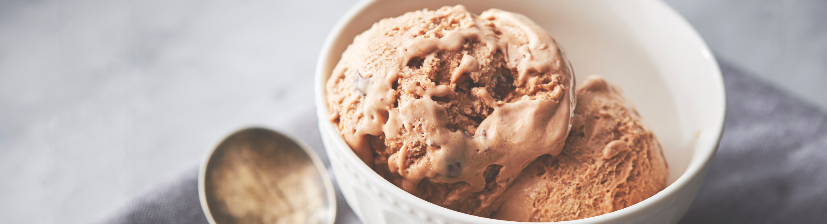 Homemade chocolate ice cream in a white bowl with an antique spoon