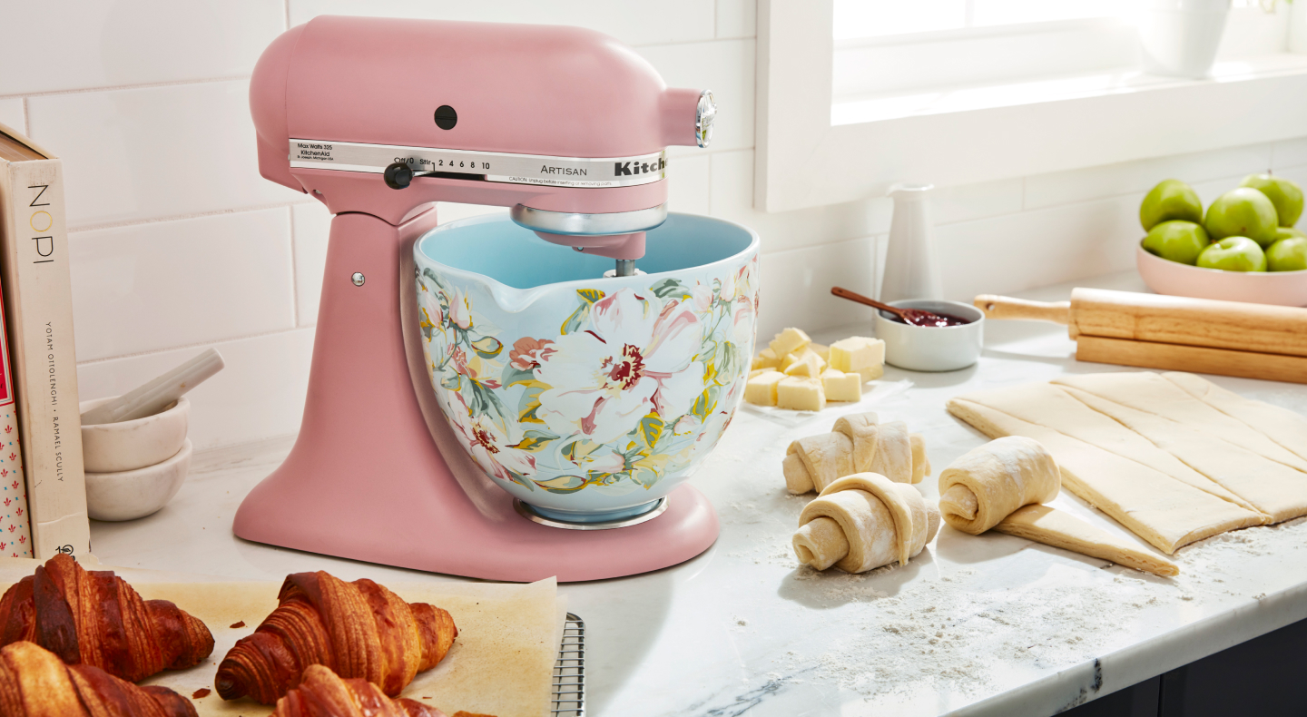 Pink KitchenAid® stand mixer with patterned bowl next to croissant dough