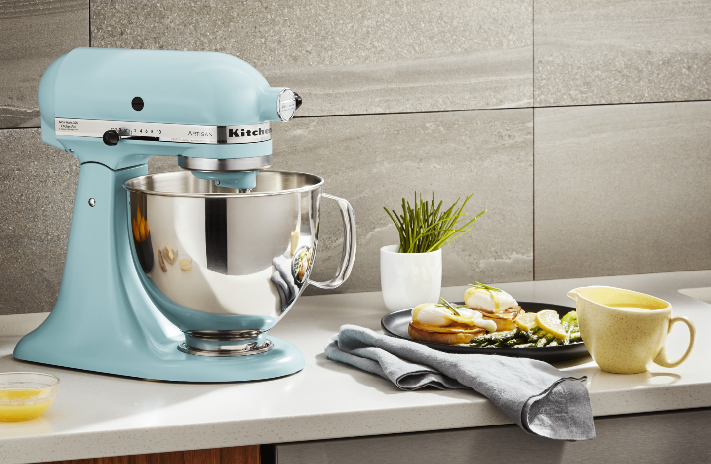A stand mixer sitting next to a plate of eggs benedict