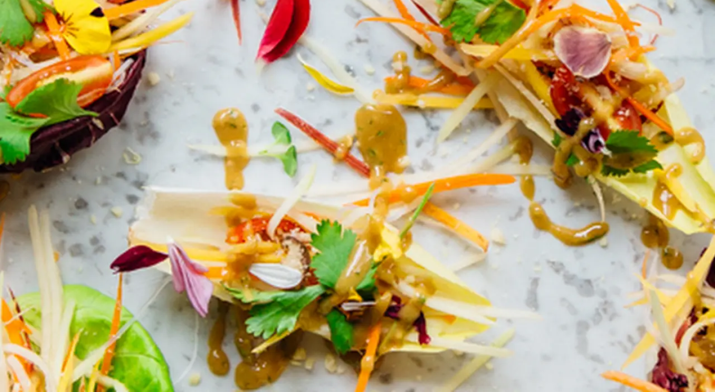 Appetizers topped with shredded vegetables and fresh herbs